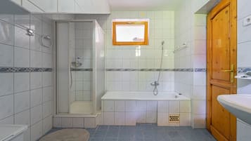 A bathroom with a shower, bathtub, and a wooden door.