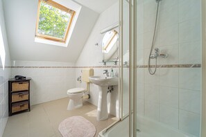 Ein Badezimmer mit Oberlicht, Toilette, Waschbecken und Dusche.