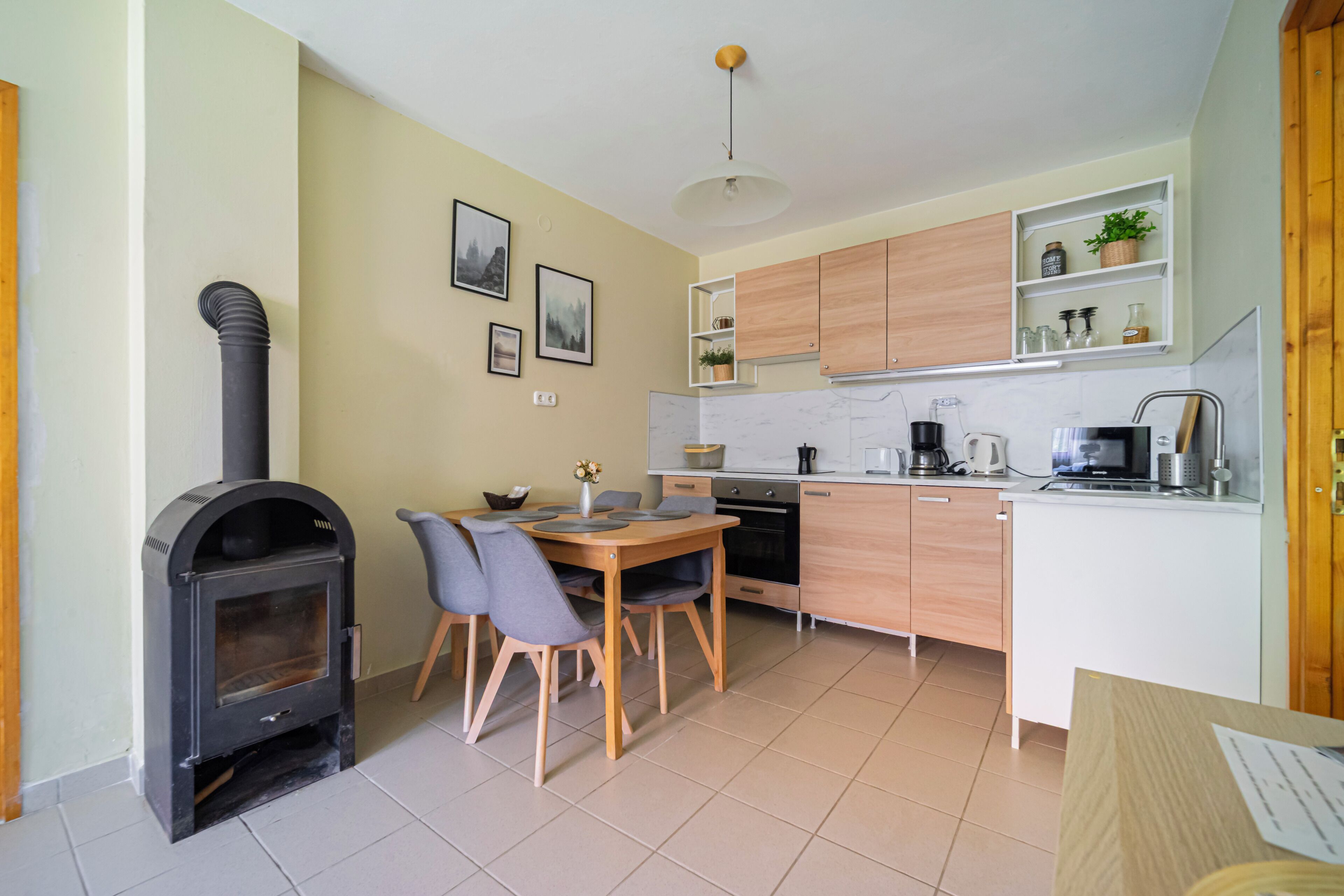 A compact kitchen with a wood-burning stove, a dining table with chairs, and a small island with a sink.