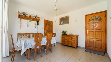 Un coin repas comprenant une table et des chaises en bois, un buffet en bois et une porte ornée d’un motif en forme de cœur.