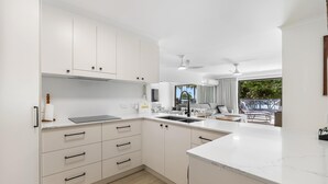 Une cuisine moderne avec des meubles blancs, un plan de travail et une vue sur un balcon.