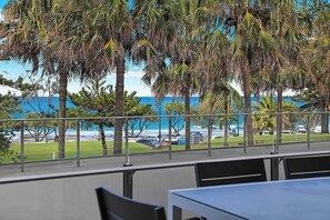 Une vue depuis un balcon doté d’une balustrade, donnant sur un parking et une étendue d’eau.