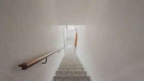 A staircase with a handrail and a view of a room at the top.