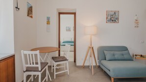 A room with a bed, a desk with two chairs, a lamp, and artwork on the walls.