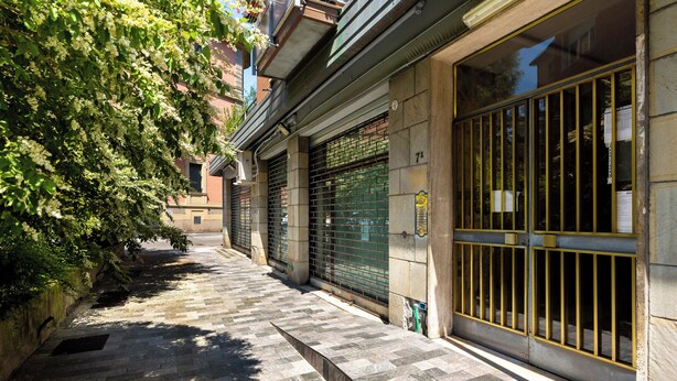 A narrow, stone-paved alley with closed metal gates and a tree-lined path. - Sant'Isaia Apartment by Wonderful Italy (Bologna)