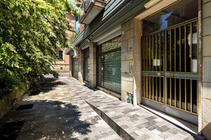 A narrow, stone-paved alley with closed metal gates and a tree-lined path. - Sant'Isaia Apartment by Wonderful Italy (Bologna)