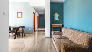 A room with a dining table and chairs, a sofa, a mirror, and a hallway leading to another room. - Sant'Isaia Apartment by Wonderful Italy (Bologna)