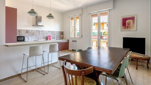A modern kitchen with a dining area, featuring a large wooden table, chairs, and pendant lights. - Sant'Isaia Apartment by Wonderful Italy (Bologna)