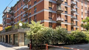 A multi-story residential building with balconies, a gated entrance, and a bicycle parked outside. - Sant'Isaia Apartment by Wonderful Italy (Bologna)