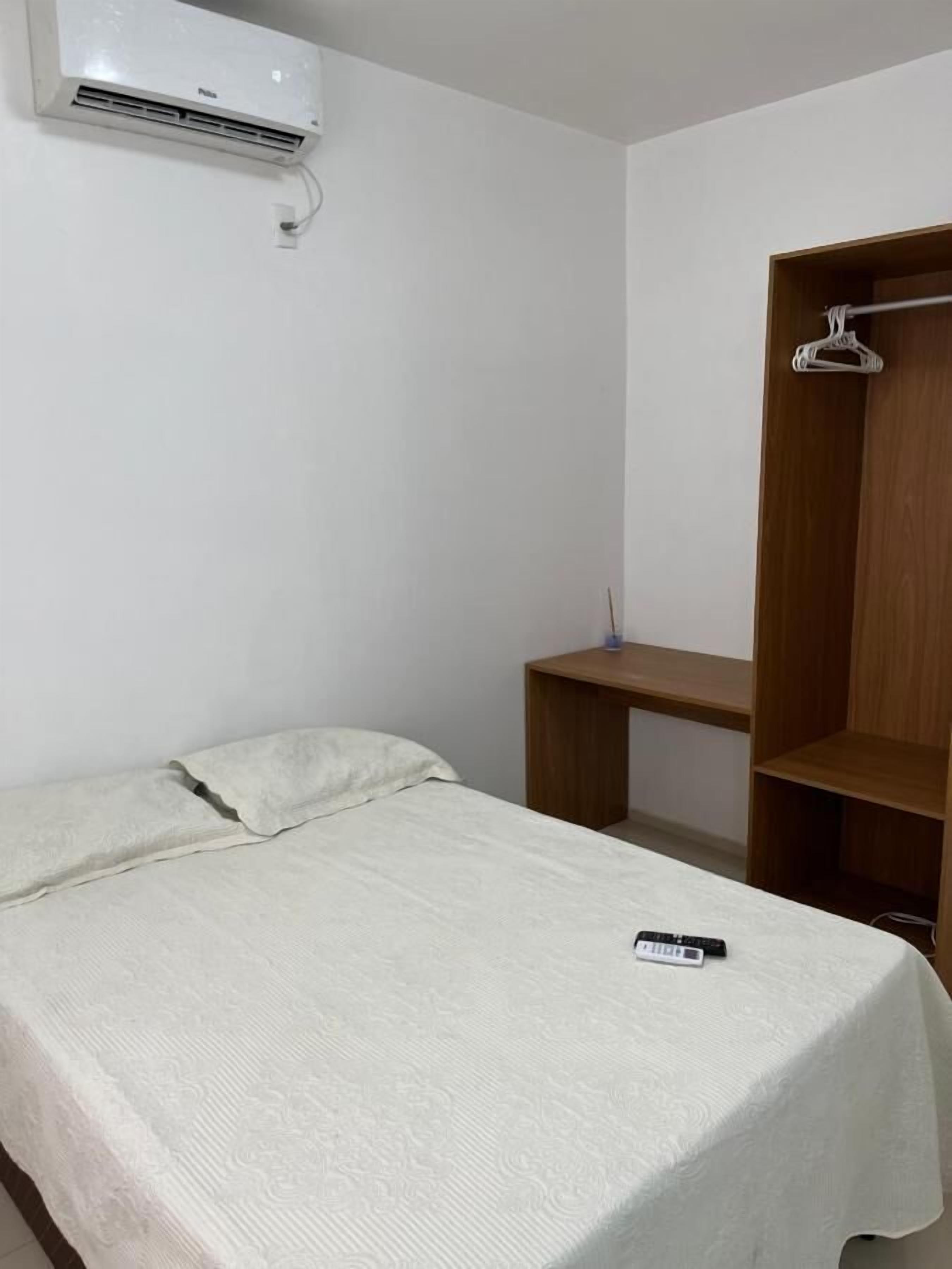 A simple room with a bed, a wooden desk, and a wardrobe.