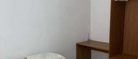 A simple room with a bed, a wooden desk, and a wardrobe.