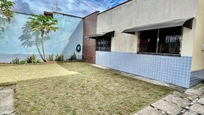 Un edificio moderno con fachada de tejas, un patio cubierto de césped y un camino pavimentado.