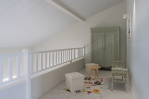 A room with a white ceiling, a white railing, a green door, a white bench, and a floral rug.