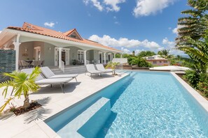 A swimming pool with lounge chairs and a covered patio area.
