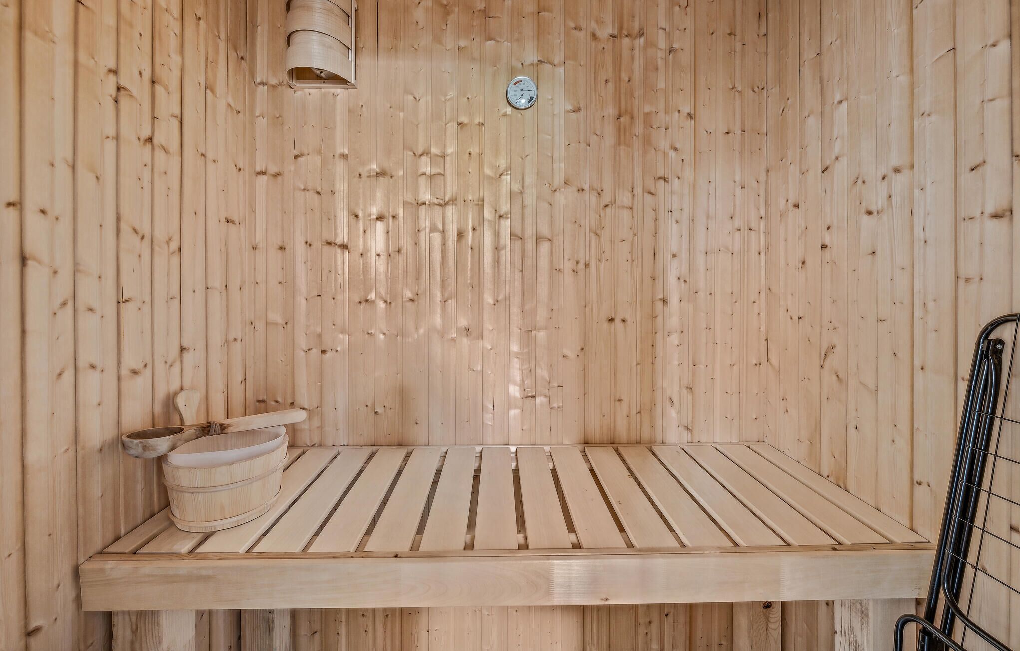 Un sauna en bois avec un banc et un petit seau en bois.