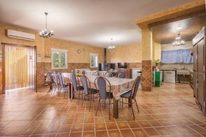 Una cocina amplia con zona de comedor, que cuenta con piso de baldosas, vigas de madera y una isla central.
