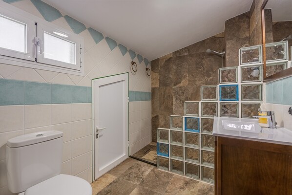 Ein Badezimmer mit Toilette, Waschbecken, Duschbereich und einer Tür.