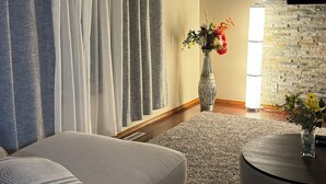 Ein Wohnzimmer mit einer Couch, einem runden Couchtisch, einer Blumenvase und einer Steinwand.