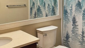 Ein Badezimmer mit Toilette, Waschbecken und einer Duschvorhang mit Waldmotiv.