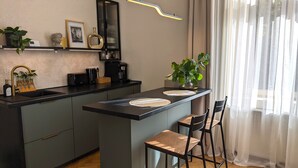 A modern kitchen with a central island, bar stools, a coffee machine, and a potted plant. - Elegant Studio in the Historic Center, AC, Quiet Area (Sibiu)