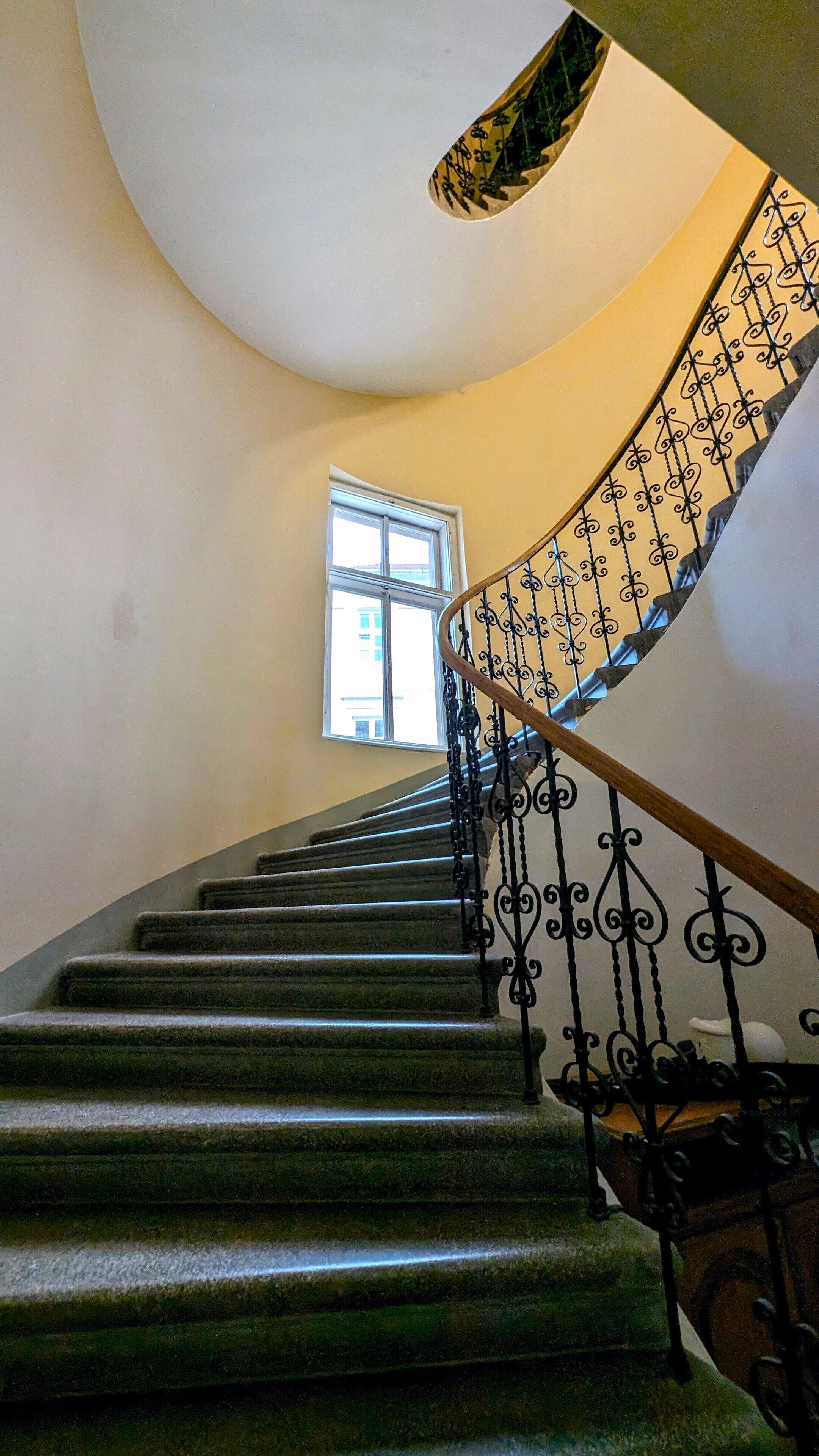 Eine Treppe mit einer geschwungenen Handläufe und einem Fenster am oberen Ende.