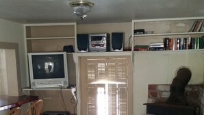 A living room with a television, bookshelf, and a fireplace. - Beaufort Harbour Suites West Lodge (Beaufort)