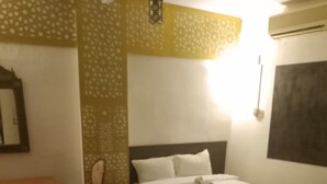 A hotel room with a bed, a desk, a chair, a patterned rug, and an air conditioning unit. - Terrific 4-bedroom hotel in Luxor with AC, WiFi and swimming pool  (Luxor)