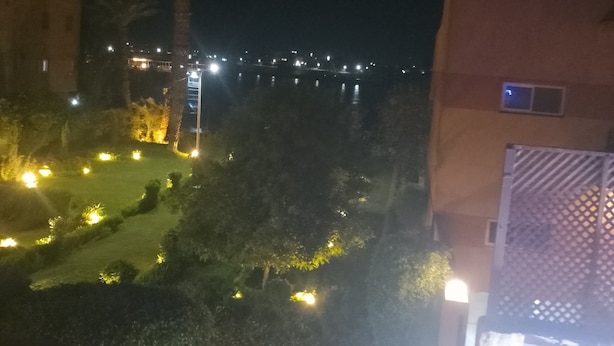 A nighttime view of a residential area with illuminated buildings and a well-lit garden area. - Terrific 4-bedroom hotel in Luxor with AC, WiFi and swimming pool  (Luxor)