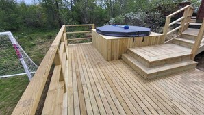 Eine Holzterrasse mit Whirlpool und Treppen zu einem weiteren Terrassenbereich.