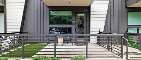 A modern building with a balcony, outdoor seating, and a well-maintained lawn.