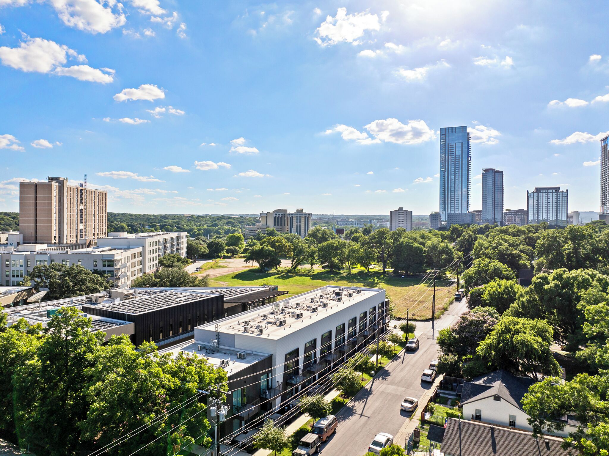 Un paysage urbain avec des bâtiments modernes, un ciel dégagé et un mélange d’espaces urbains et de zones vertes.