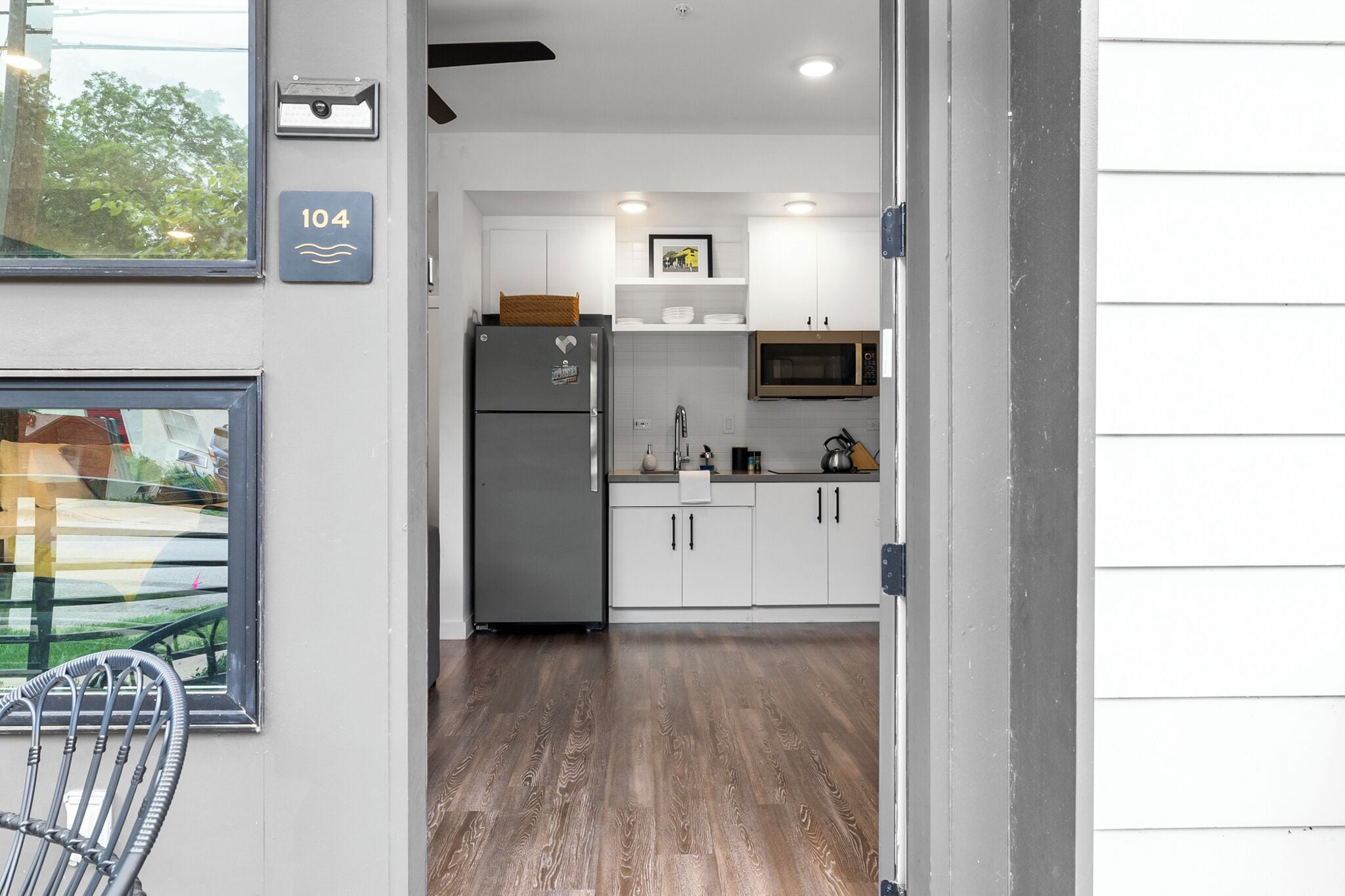 A modern kitchen with white cabinets, a stainless steel refrigerator, and a microwave.