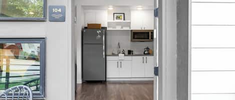 A modern kitchen with white cabinets, a stainless steel refrigerator, and a microwave.
