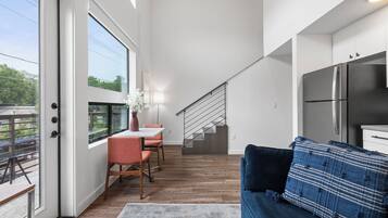 A modern living space with a kitchen, dining area, and a staircase leading to an upper level.