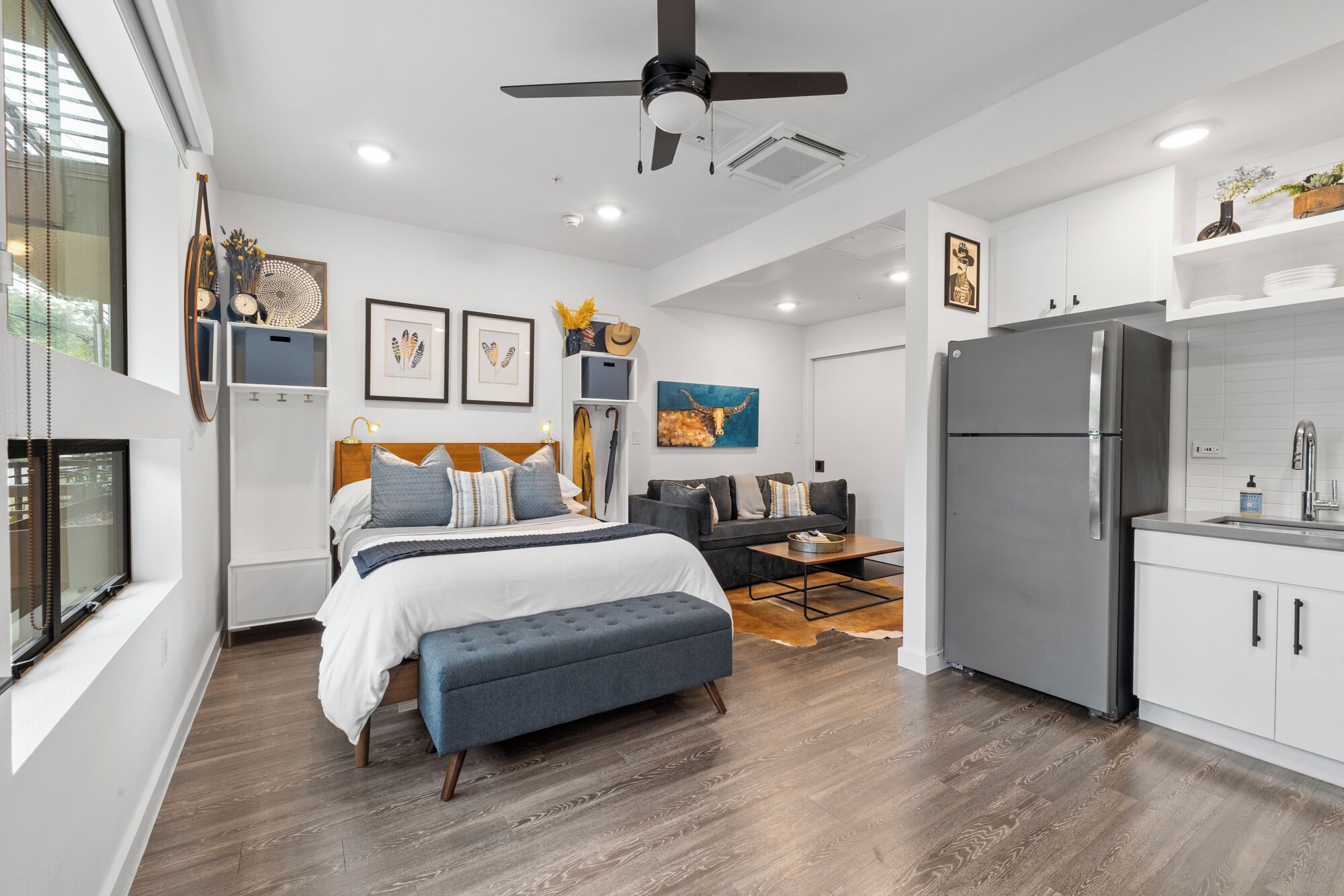 Ein modernes, kleines Schlafzimmer mit Bett, Nachttischen und Deckenventilator.