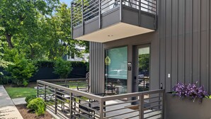 A modern building with a balcony, a glass door, and a small garden area. - Holly House (Austin)