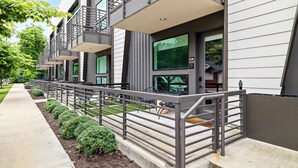 A modern building with outdoor seating and a metal railing. - Holly House (Austin)