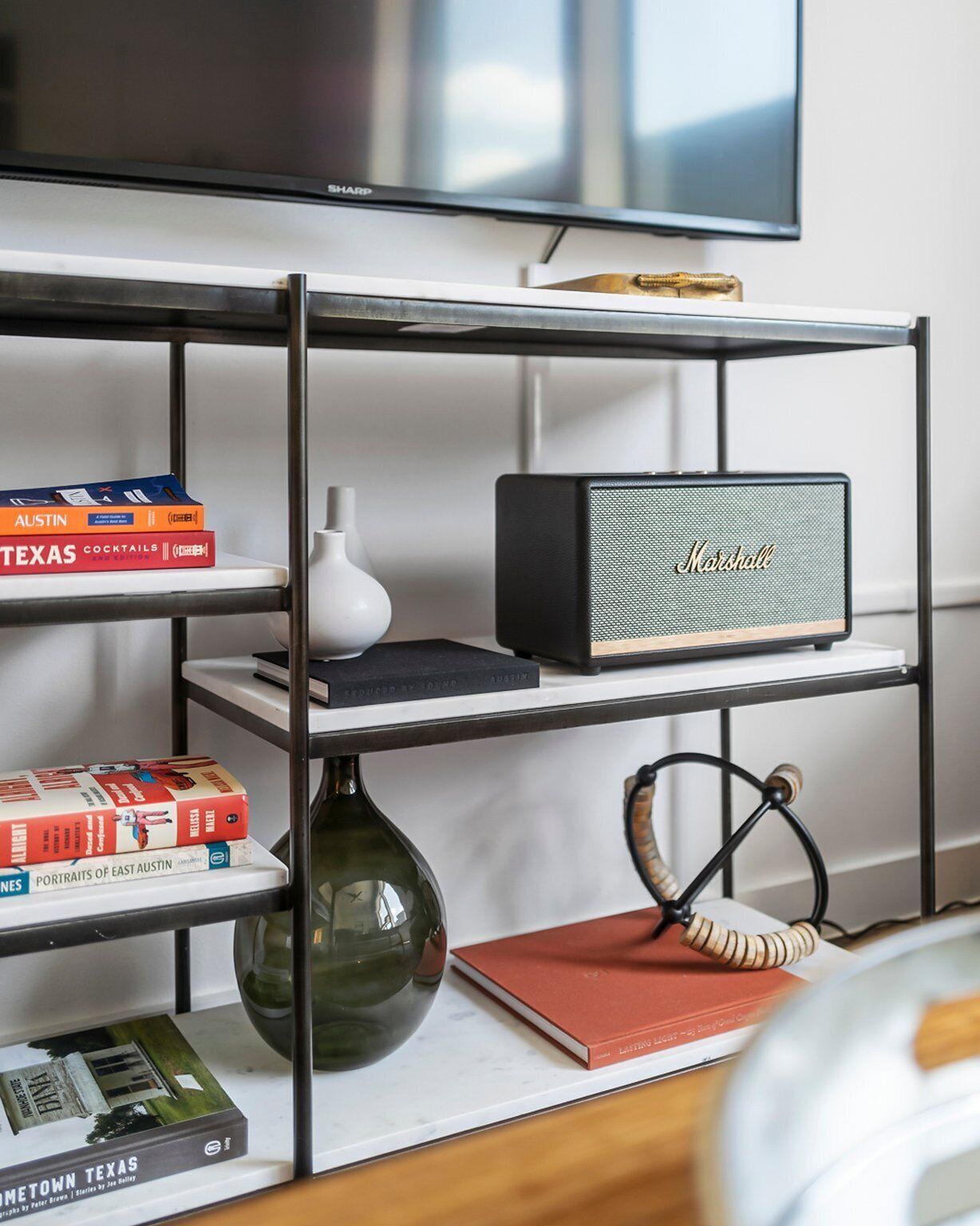 Une bibliothèque remplie de livres, un vase, une lampe et un haut-parleur Marshall.