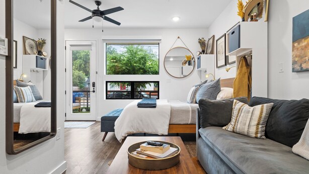 A modern living room with a sofa, a coffee table, and a bed with a view of the outdoors. - Holly House (Austin)