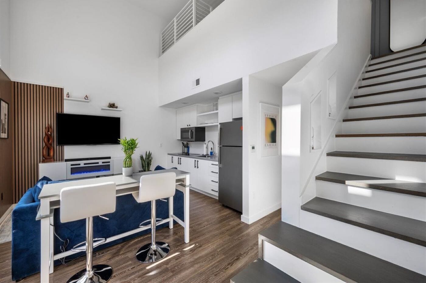 Un apartamento moderno con cocina, comedor y escalera.