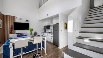 Un apartamento moderno con cocina, comedor y escalera.