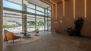 Un hall d’entrée moderne avec des murs en verre, un mur d’accent en bois et un espace salon comprenant deux fauteuils et une table.