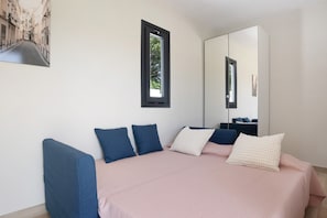A bedroom with a bed, pillows, a window, and a mirror.