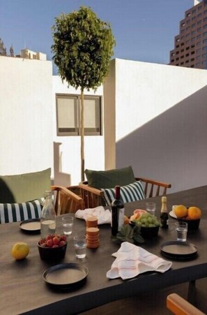 Enjoy al fresco dining in a serene outdoor space with a table set amidst lush greenery and comfortable seating.