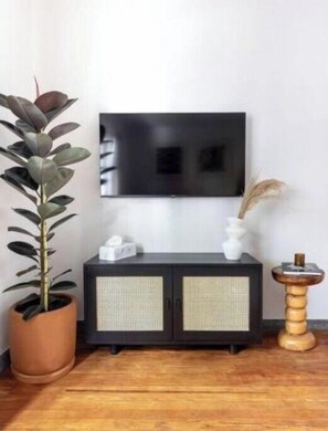 Relax in this stylish living room with a flat-screen TV, potted plant, and elegant cabinet.
