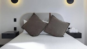Een moderne slaapkamer met een bed, twee kussens, nachtkastjes en wandlampen.