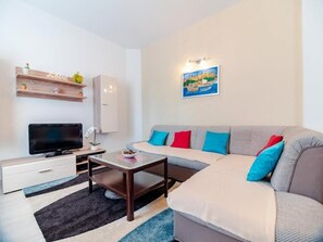 A modern living room with a sofa, a TV, a coffee table, and a painting on the wall. - Apartment Stella in center of Medulin for 6 person. (Medulin)