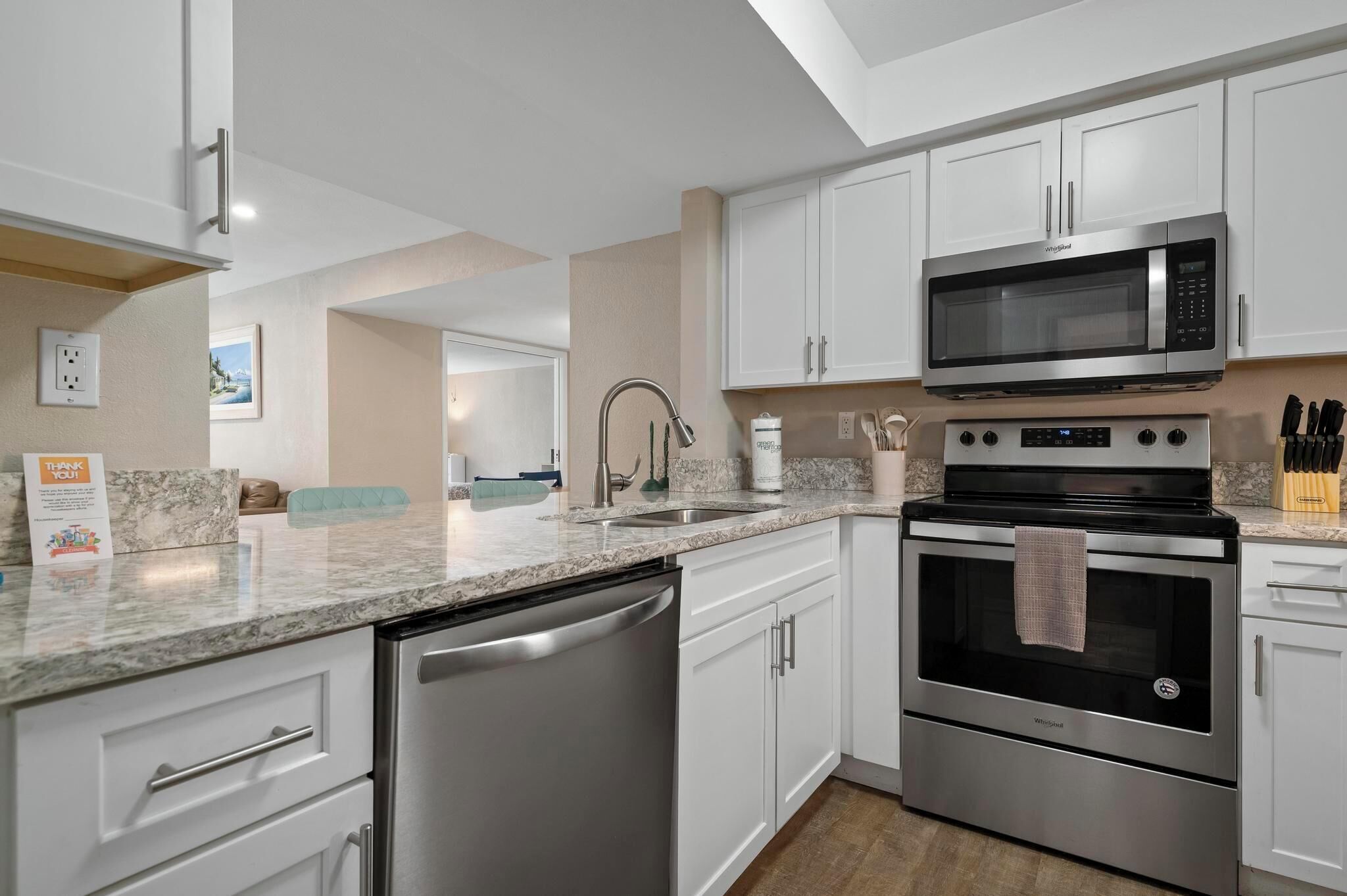 A modern kitchen with white cabinets, stainless steel appliances, a dishwasher, and a microwave.