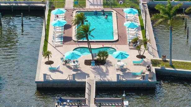Une piscine rectangulaire entourée d’une terrasse, de chaises longues et de parasols.