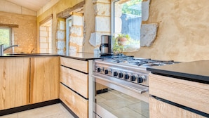 Une cuisine avec des meubles en bois, une cuisinière en acier inoxydable et une fenêtre donnant sur l’extérieur.
